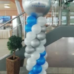 Ballonsäule anlässlich eines Firmen Jubiläums mit weißen, silbernen und blauen Ballons. Auf der Spitze dekoriert mit einem bedruckten Riesenballon in Silber Ballonsäule mit silbernen und weißen und blauen Ballons und auf der Spitze ein großer Silberfarbener Ballon mit Aufdruck